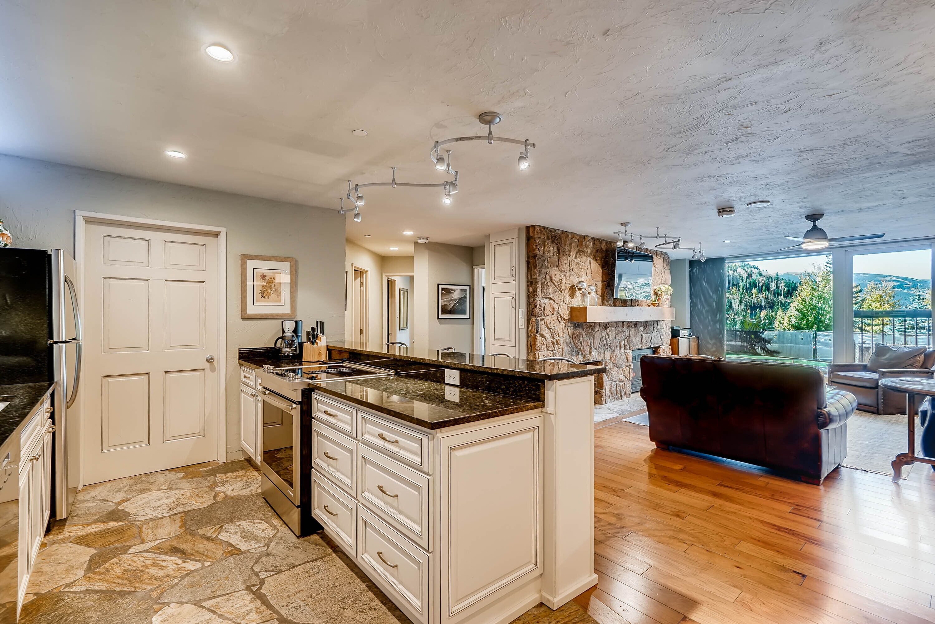 A spacious kitchen with white cabinetry, a granite countertop, and a stone backsplash.