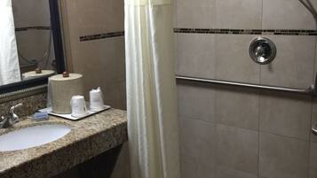 A bathroom with a sink, mirror, and shower.