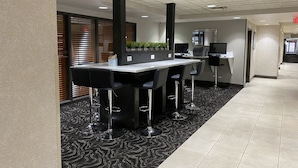 A modern hotel lobby with a reception desk, bar area with stools, and a patterned carpet. - Wingate by Wyndham Little Rock (Little Rock)