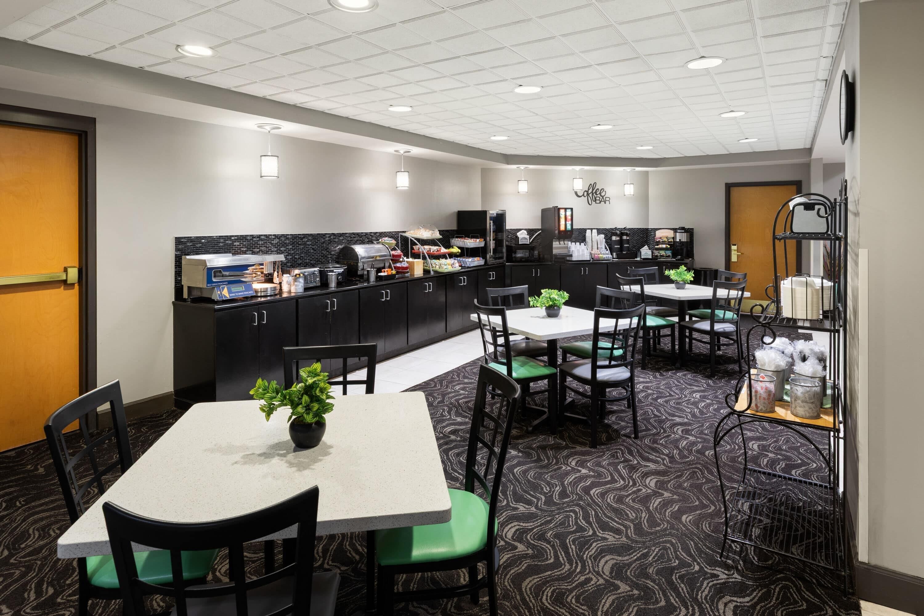 Uma área de refeições moderna em hotel, com buffet, arranjos de assento e um bar de café.