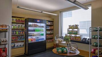 A snack and beverage section with a refrigerated display, shelves stocked with snacks, and a window view.