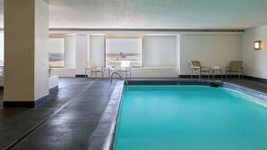 Une piscine intérieure offrant une vue sur un paysage lointain grâce à de grandes fenêtres.