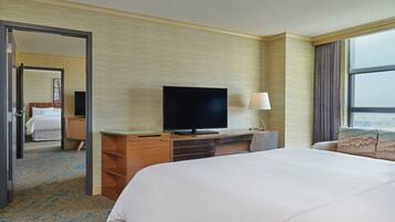 A hotel room with a bed, a TV, a desk, and a window.