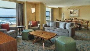 Une chambre d’hôtel avec un canapé, des fauteuils, une table à manger et une vue sur la ville.