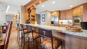 A kitchen with wooden cabinets, a granite countertop, and a stainless steel refrigerator. - Oxford Court by East West Hospitality (Avon)