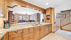 A spacious kitchen with wooden cabinets, granite countertops, and a built-in island. - Oxford Court by East West Hospitality (Avon)