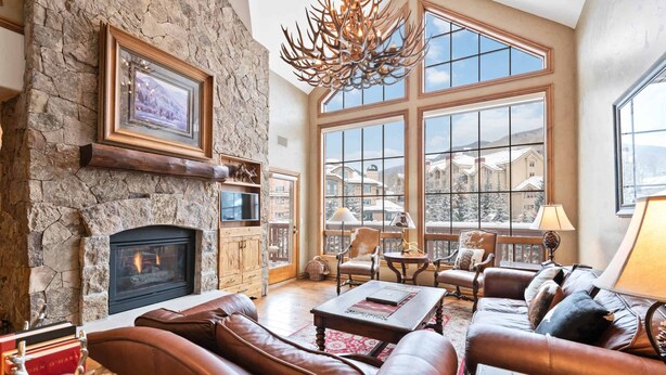 A spacious living room with a stone fireplace, leather sofas, and large windows offering a view of the surrounding area. - Oxford Court by East West Hospitality (Avon)