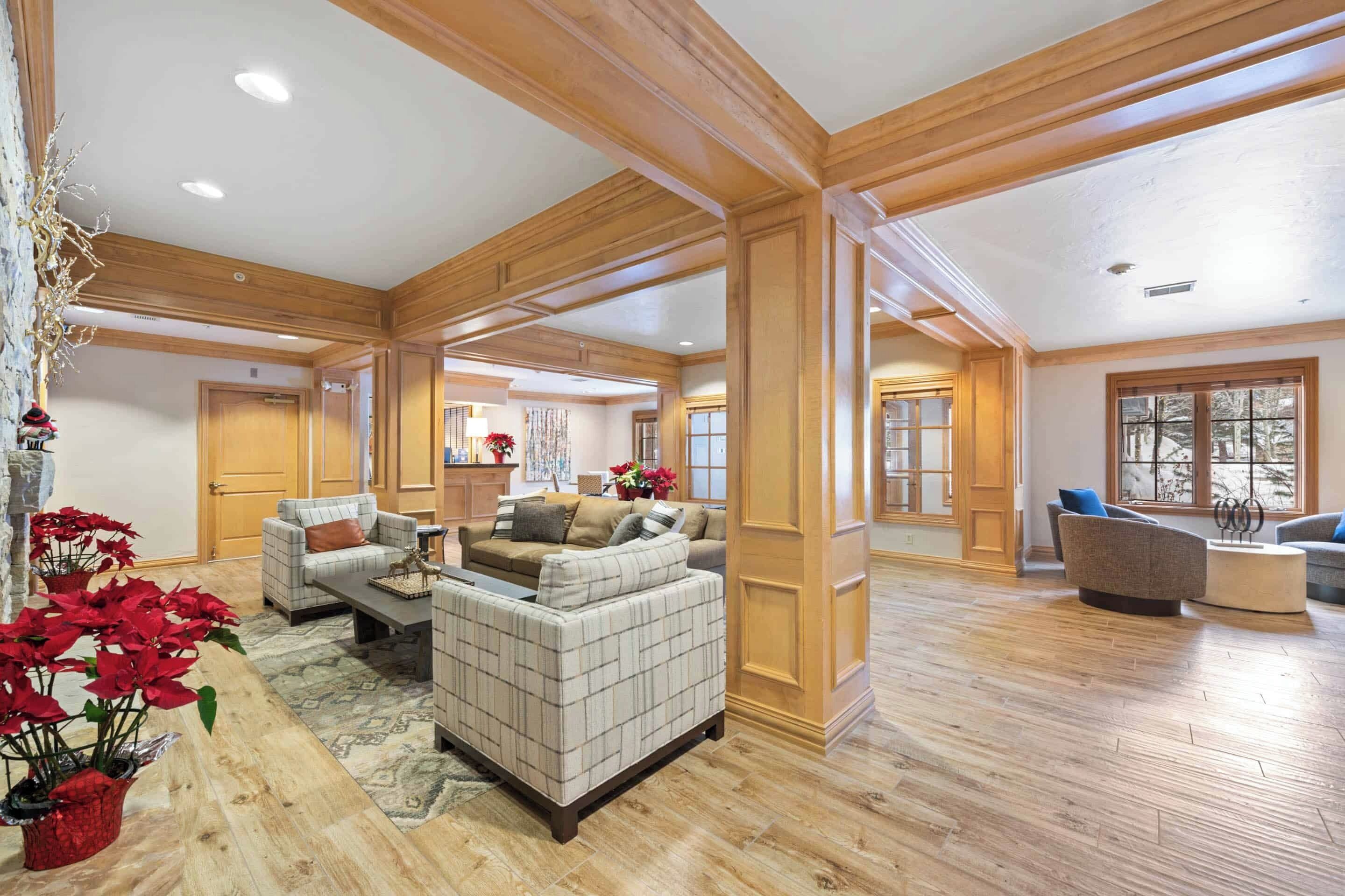 A spacious living room with wooden beams, a fireplace, and a large window.