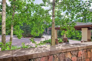 Un muro de piedra con una pérgola y follaje verde.