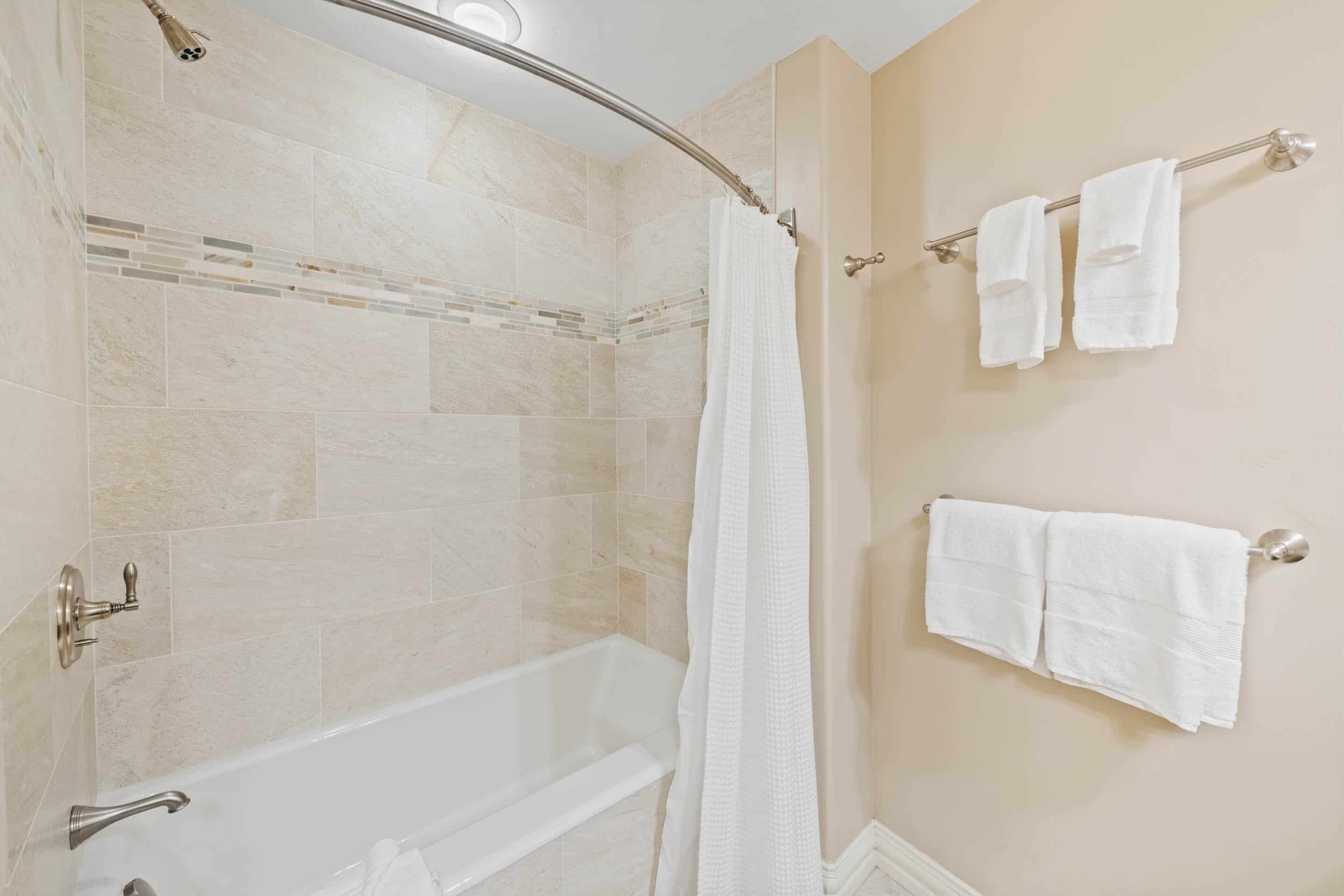 Un bagno con una vasca, una tenda da doccia e due asciugamani appesi a un portascopevoli.