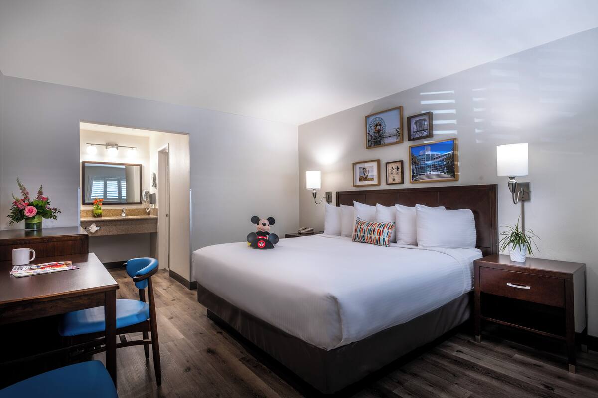 Ein Hotelzimmer mit einem großen Bett, einem Schreibtisch mit Stuhl, einem Nachttisch und einem Spiegel.