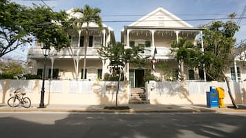 A two-story house with a balcony, a bicycle parked on the sidewalk, and a mailbox.
