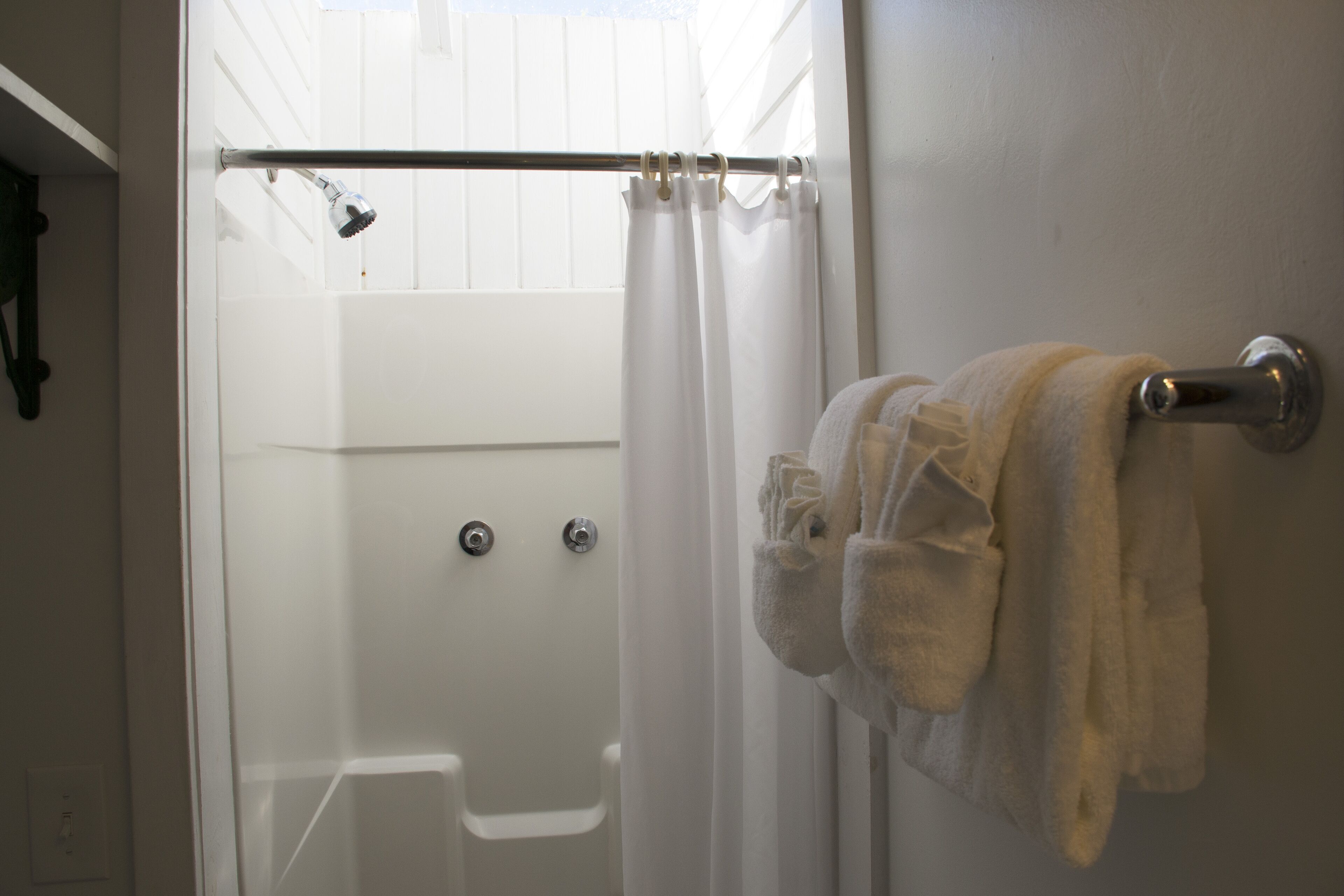 Un baño con ducha, bañera y toallero con toallas.