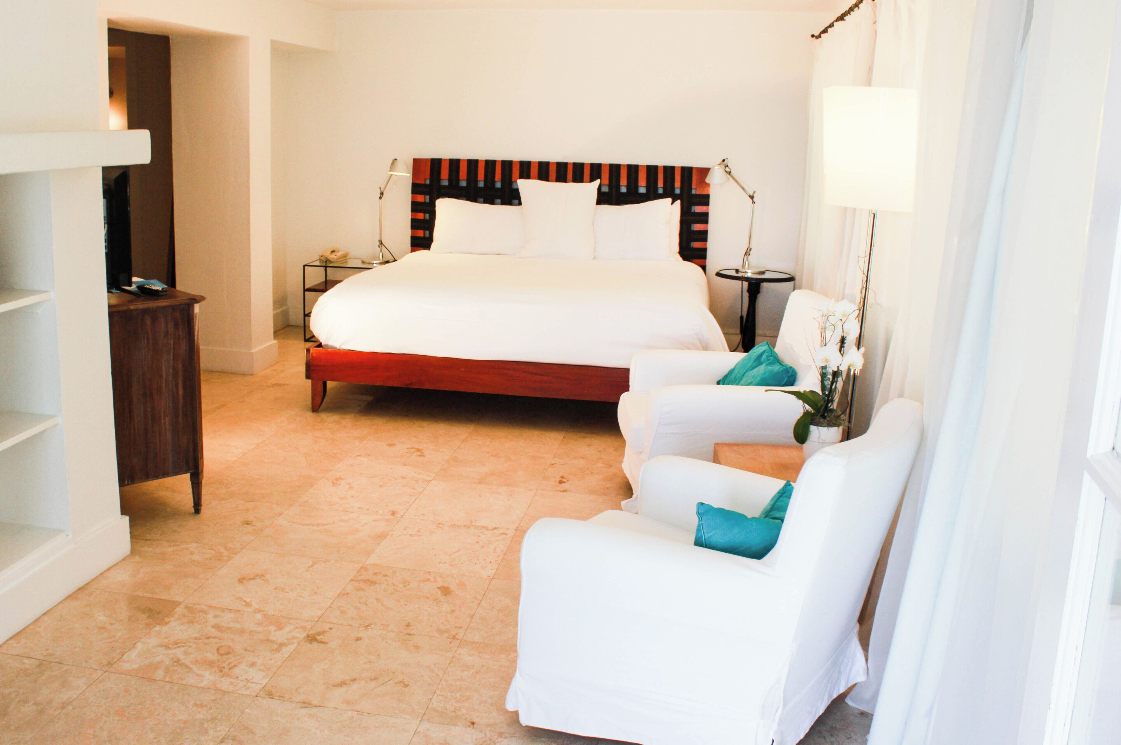 Een hotelkamer met een groot bed, een bureau, een stoel en een klein tafeltje met een lamp.