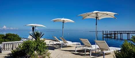 Una playa cerca, arena blanca, sillas reclinables de playa, sombrillas