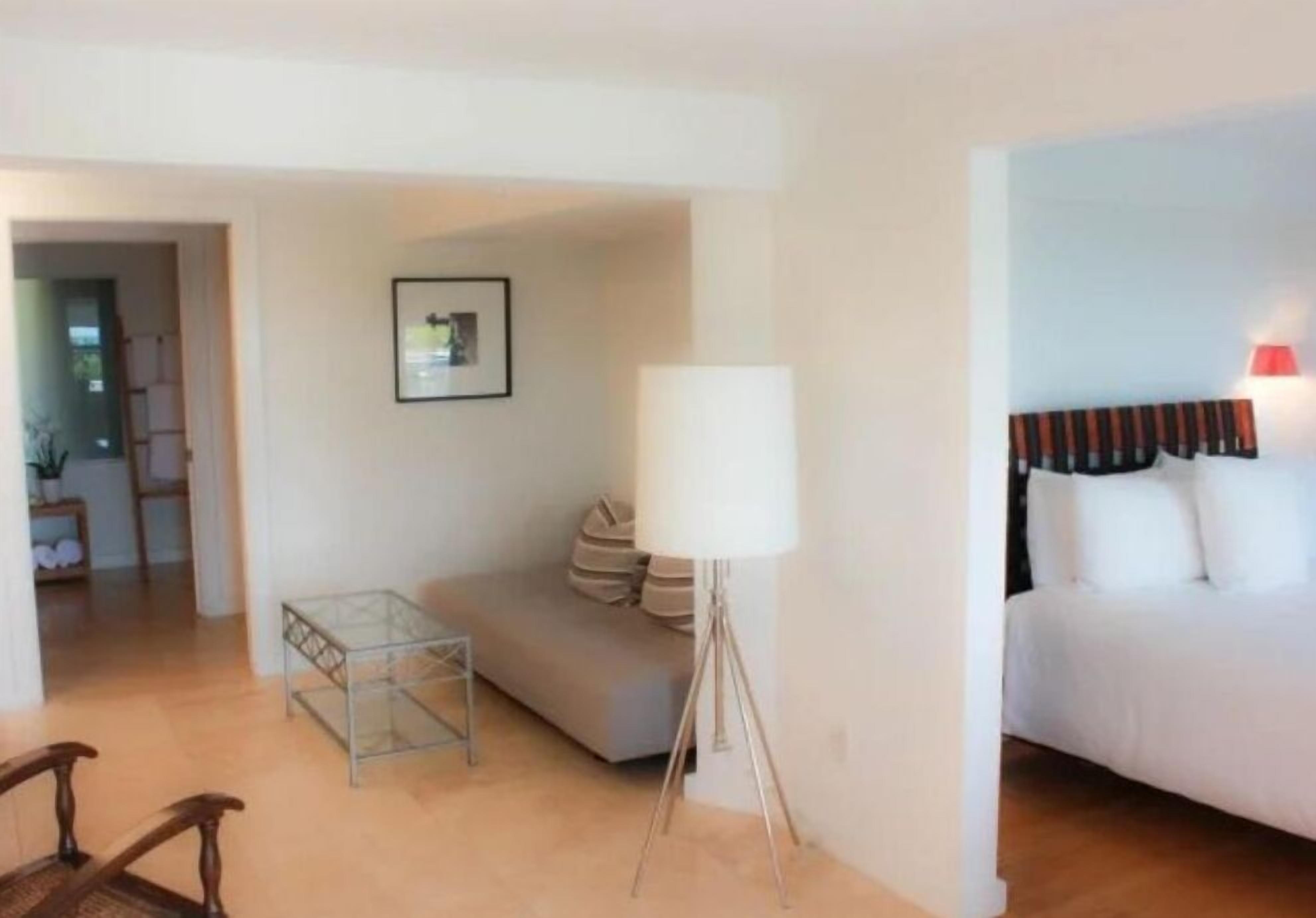 Une chambre d’hôtel avec un lit, un canapé blanc, une petite table et une lampe.