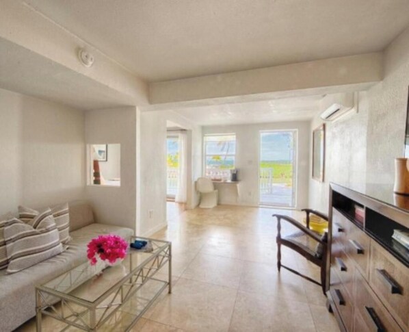 A spacious living area with a sofa, coffee table, and a chair. There is a large window providing a view of the outdoors.