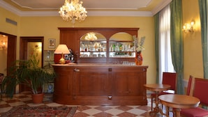 A bar area with a wooden counter, a chandelier, and a potted plant. - Hotel Villa Cipro (Venice)