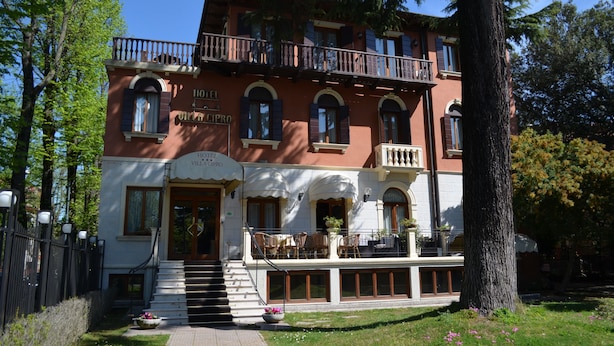 A two-story hotel with a balcony, a staircase leading to the entrance, and outdoor seating. - Hotel Villa Cipro (Venice)