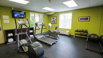 A gym with treadmills, stationary bikes, and a weight rack.