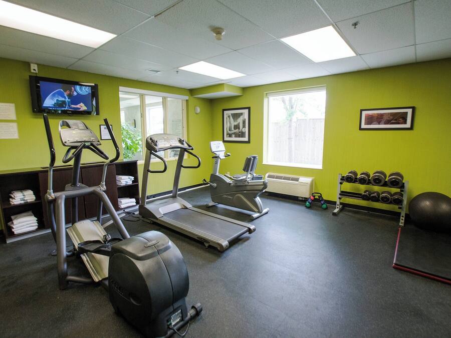 A gym with treadmills, stationary bikes, and a weight rack.