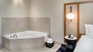 A modern bathroom with a large bathtub, a bedside table with a phone, and a wall-mounted light fixture. - Fairfield Inn by Marriott Toronto Oakville (Oakville)