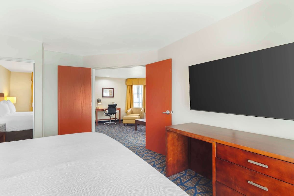 A hotel room with a large bed, a desk with a chair, a TV, and a wardrobe.
