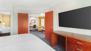 A hotel room with a large bed, a desk with a chair, a TV, and a wardrobe.