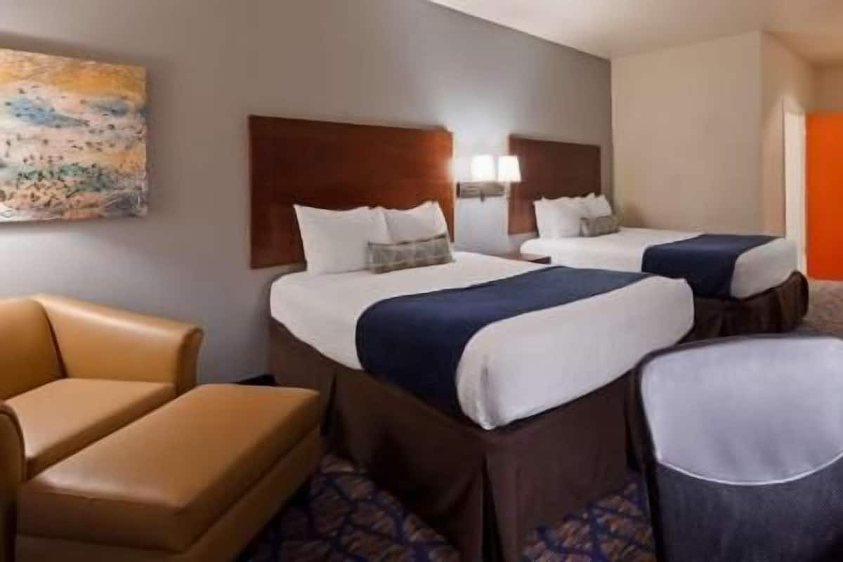 A hotel room with two beds, a sofa, a chair, and a painting on the wall.