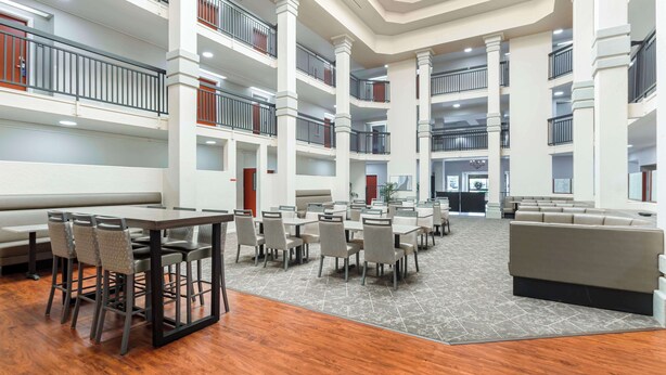 A multi-level hotel lobby with a central seating area, multiple floors, and a grand staircase. - Best Western Plus Villa Del Lago Inn Patterson (Patterson)