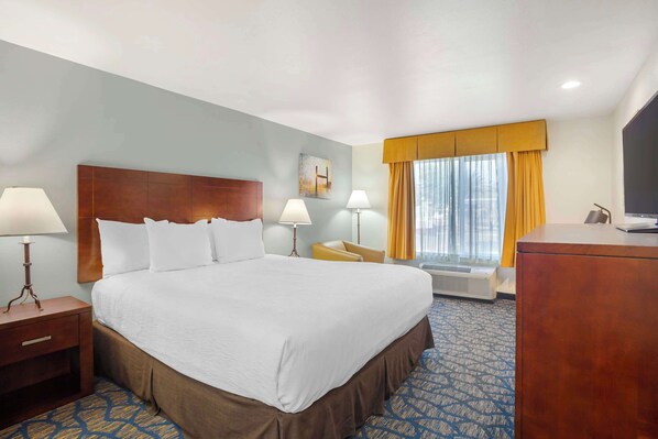 A hotel room with a large bed, two bedside tables with lamps, a desk, and a television.