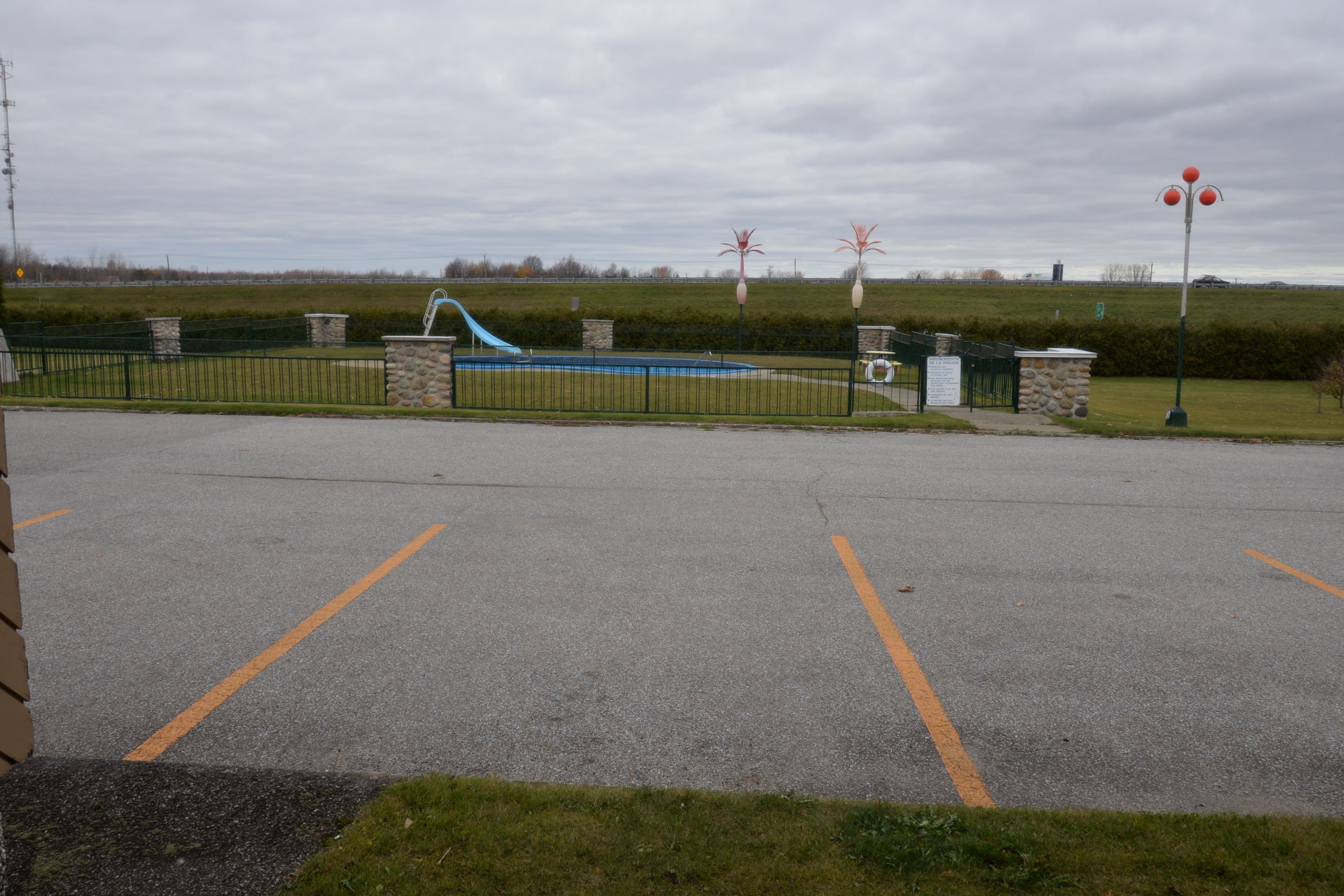 A parking lot with a blue slide and a fenced area.