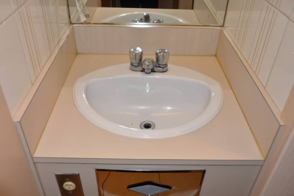 A bathroom with a white sink, chrome faucets, and a mirror above the sink.