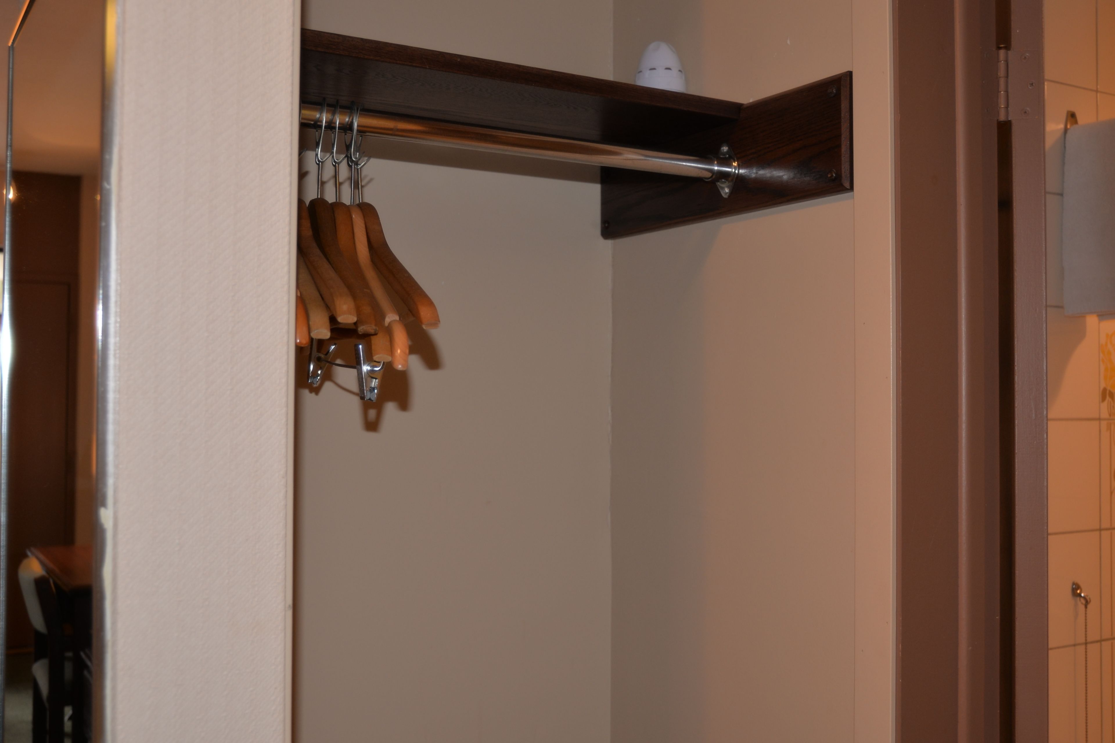 A wooden coat rack with several wooden hangers.