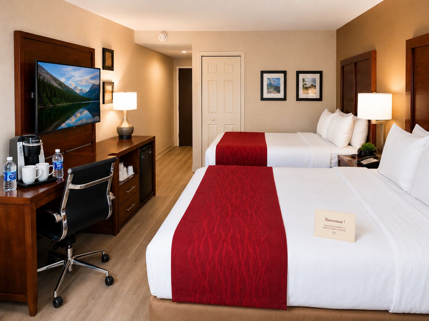 Une chambre d’hôtel avec deux lits, un bureau avec une télévision, une machine à café et une chaise.