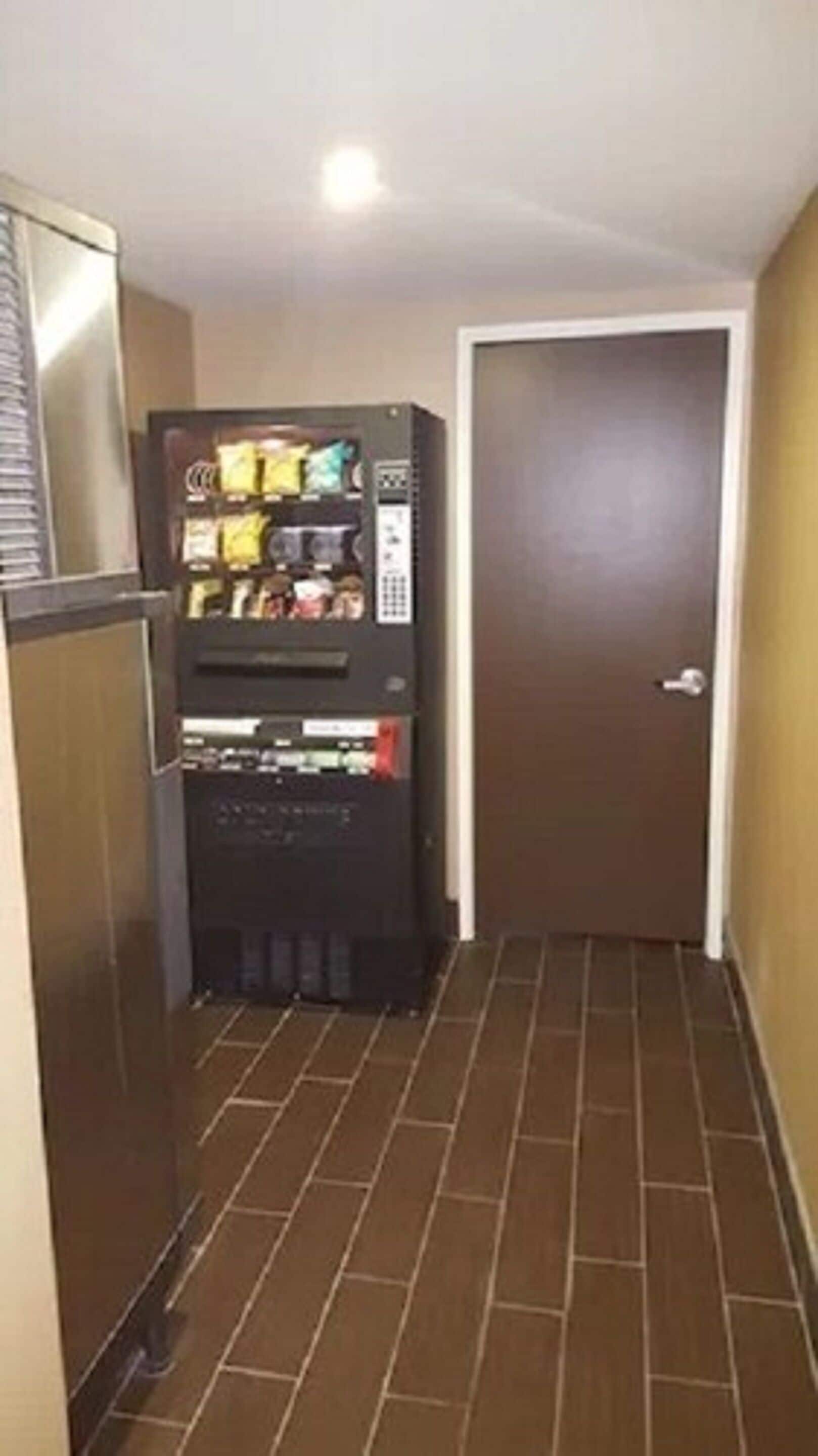 Un pasillo estrecho con una máquina expendedora y una puerta.