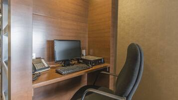 A wooden desk with a computer, keyboard, and telephone.