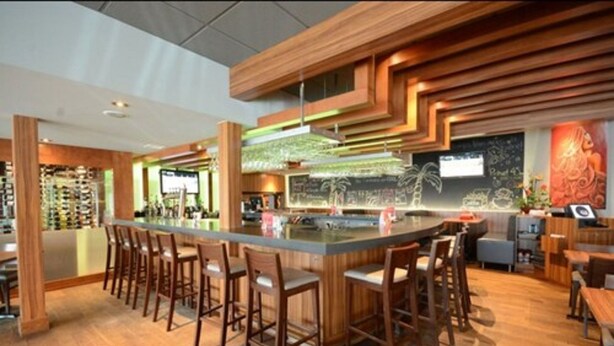 A modern bar area with a central island, bar stools, and a wooden ceiling design. - Comfort Inn (Saint Georges)