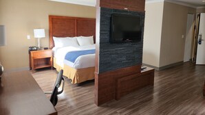 A hotel room with a bed, a desk, a chair, a television, and a wooden panel wall. - Comfort Inn (Saint Georges)