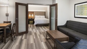 A hotel room with a bed, a sofa, a dining table, and a lamp. - Holiday Inn Express & Suites Saskatoon Centre by IHG (Saskatoon)