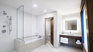 A modern bathroom with a glass-enclosed shower, a large mirror, a wooden vanity, and a white sink. - Holiday Inn Express & Suites Saskatoon Centre by IHG (Saskatoon)