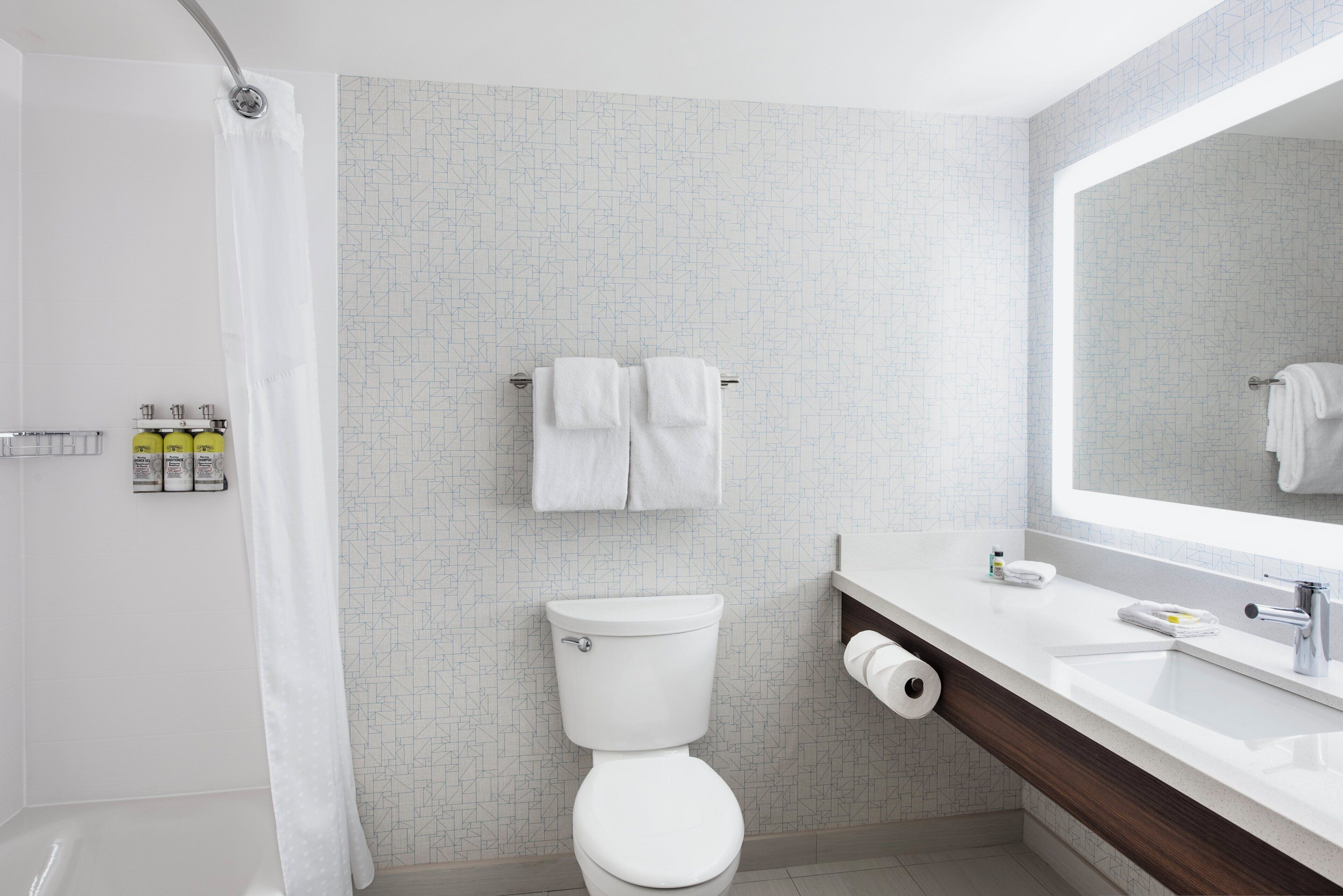 A modern bathroom with a shower, toilet, and sink.