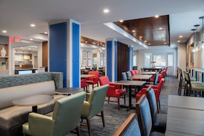 Un hall d’hôtel avec des espaces aménagés avec des sièges, des tables et un comptoir d’accueil.
