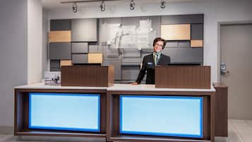 A hotel reception desk with a modern design, including a digital display and a sign for Holiday Inn Express & Suites.