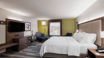 Une chambre d’hôtel équipée d’un lit, d’un bureau, d’une chaise, d’une télévision et d’une fenêtre donnant sur un paysage agréable.