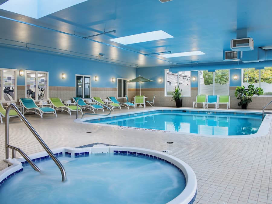 A swimming pool area with lounge chairs and a hot tub.