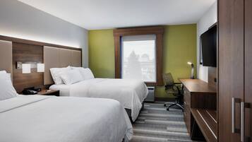 A hotel room with two beds, a desk, a chair, a TV, and a window with a view.