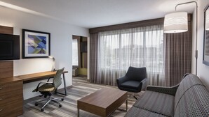 A hotel room with a desk, office chair, sofa, and a large window with curtains. - Holiday Inn Express & Suites Saskatoon Centre by IHG (Saskatoon)