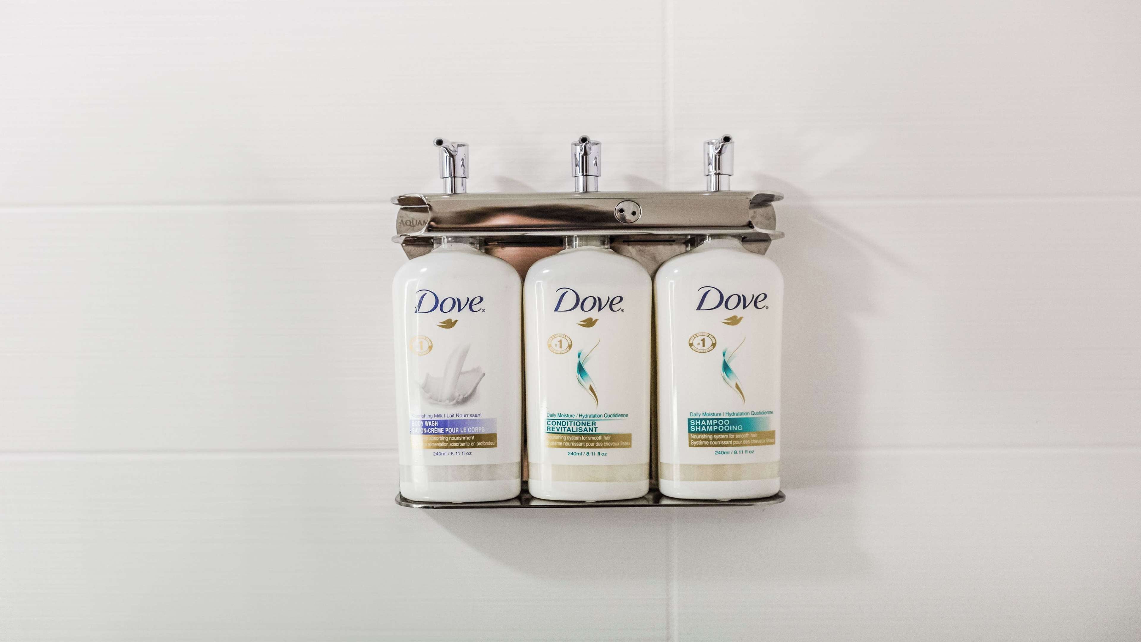 Three Dove products on a wall-mounted dispenser.