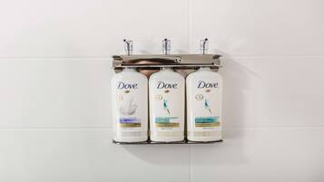 Três produtos Dove em um dispensador fixado na parede.
